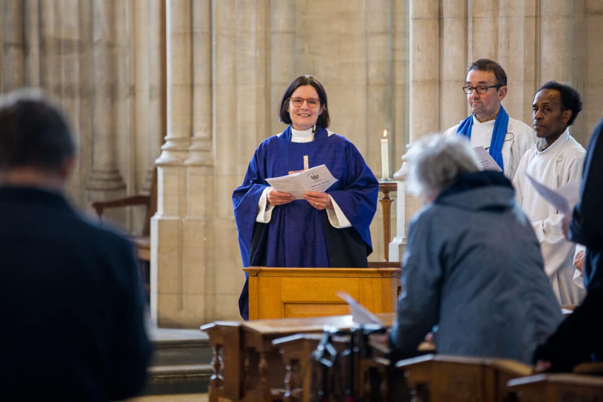 A vicar standing by a font