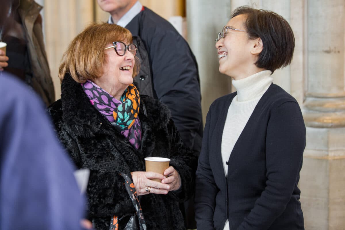 Two women in church laughing drinking coffee