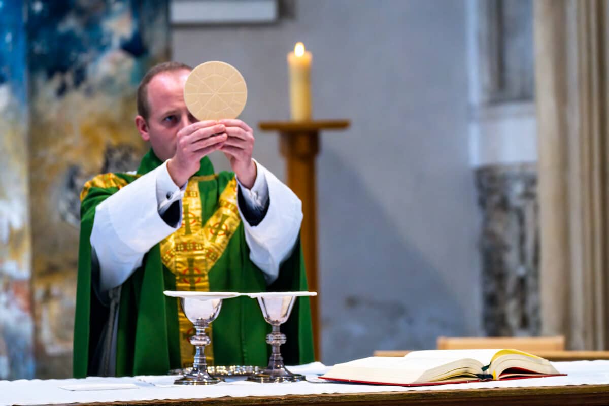 Image of a vicar lifting up communion bread