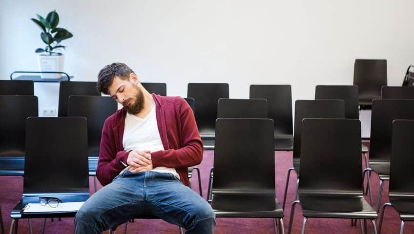 Bearded guy in brown hoodie and blue jeans sitting and sleeping