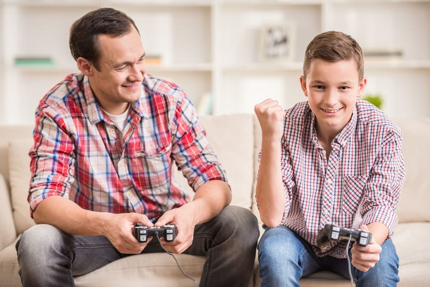 Father and son playing computer game together to help with sideways listening