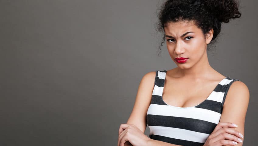 Irritated young woman standing with arms folded