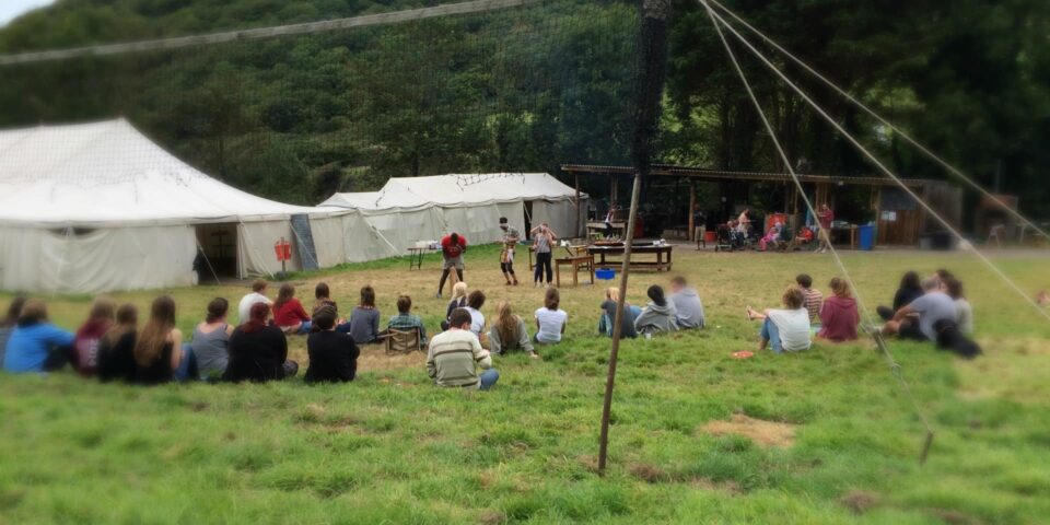 Groups of people sitting on the grass outside tents