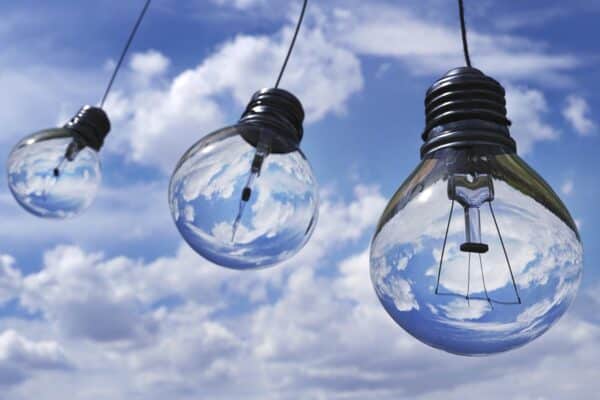 Image of lightbulbs hanging on string against blue sky.