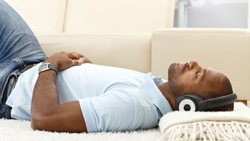 Man relaxing lying on floor with headphones on