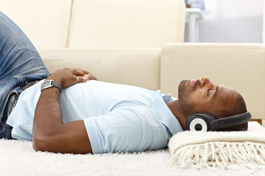 Man relaxing lying on floor with headphones on