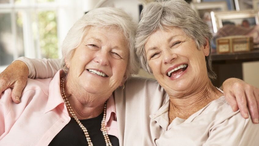 Portrait Of Two Retired Senior Female Friends Sitting On Sofa
