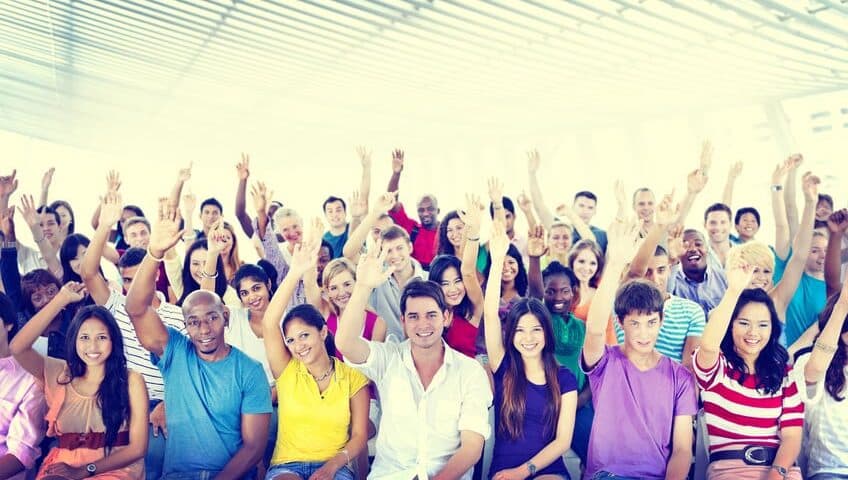 Volunteers raising hands against a blue sky