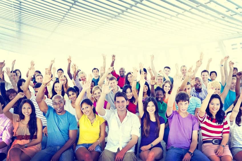 Volunteers raising hands against a blue sky