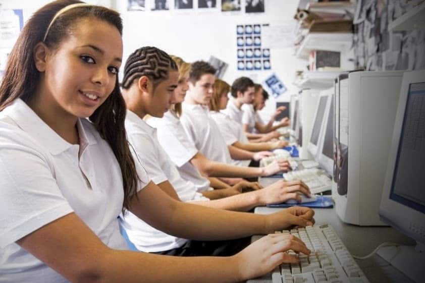 A group of young people sitting in front of computers