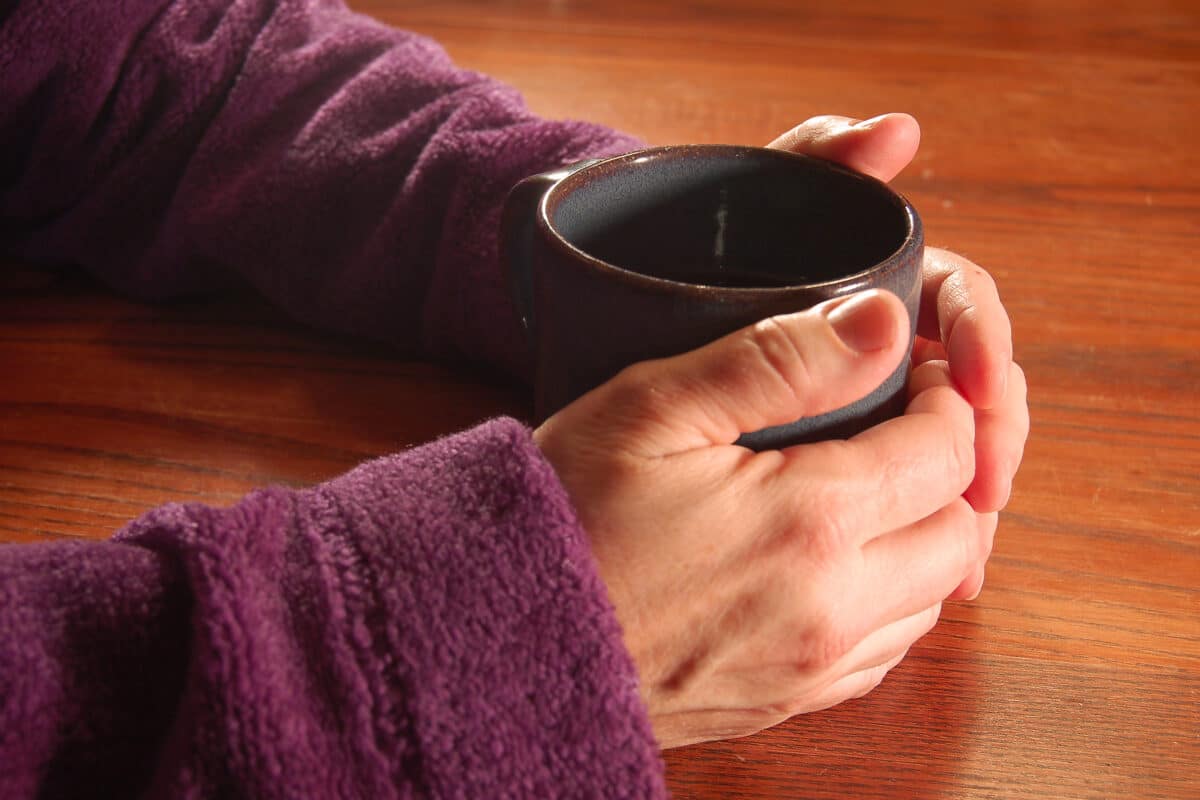 Hands around mug of tea.