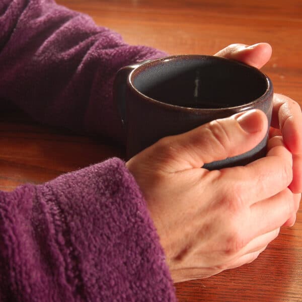 Hands around mug of tea.