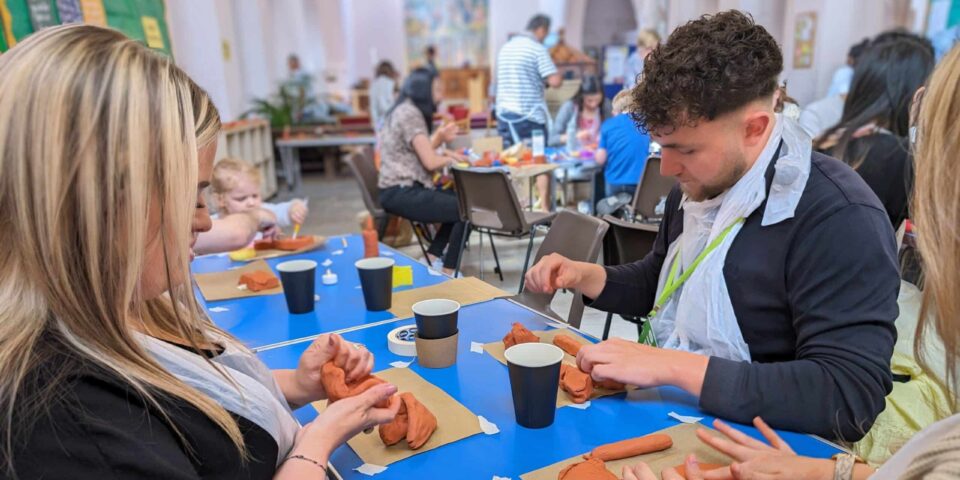 Three people at a table working with clay