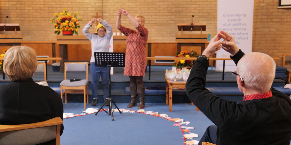 Two people at the front of WAVE church signing worship