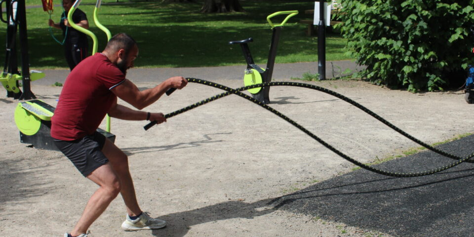 man using outdoor gym equipment ropes