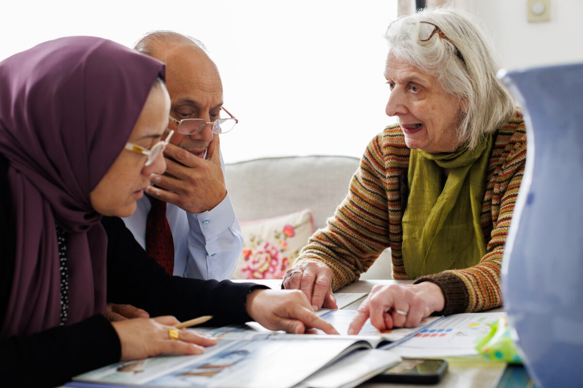 A refugee couple and and a helper around a table