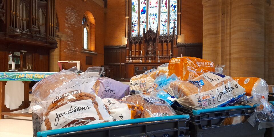 crates of bread and other groceries on a table in a church building