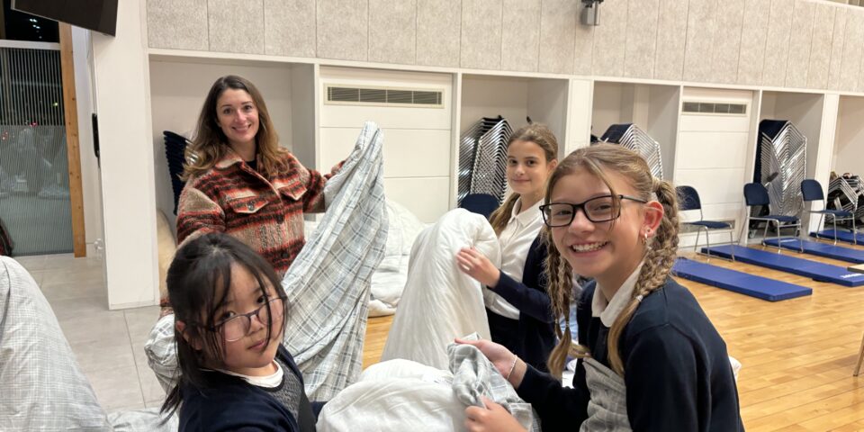 children and adults putting on duvet covers while volunteering at church night shelter