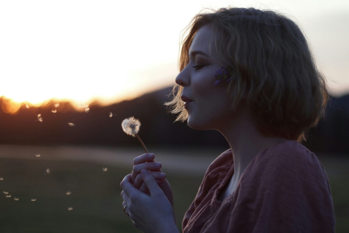 woman blowing a dandelion clock