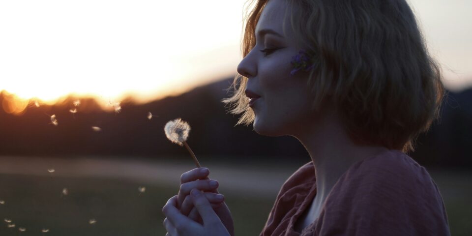 woman blowing a dandelion clock