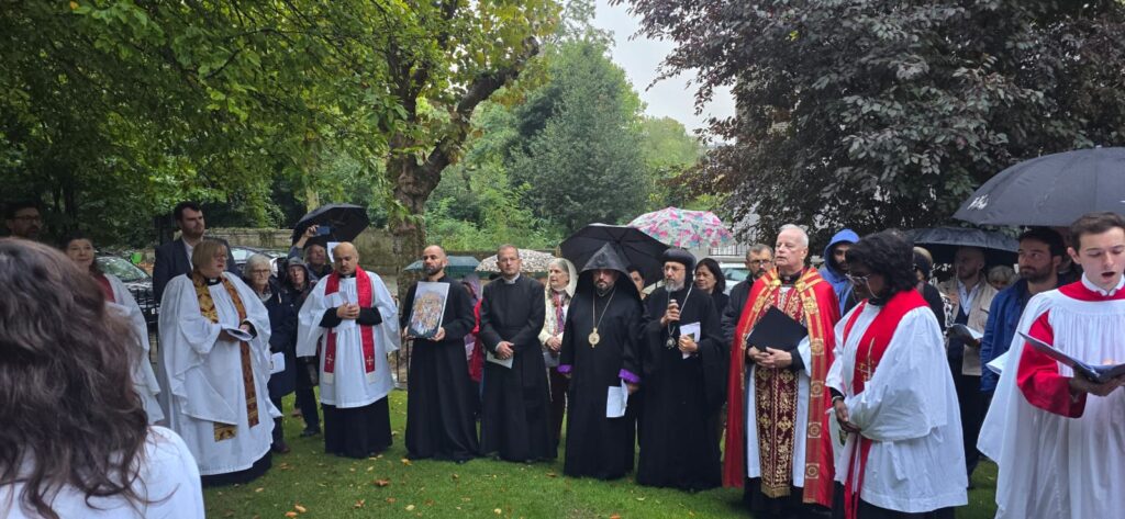 Group of clergy and choristers standing outside under tress