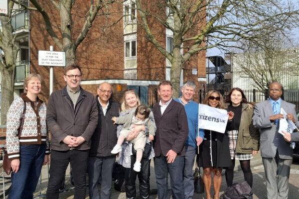 Group of residents in Ealing outside block of flats, with a "Citizens UK" flag