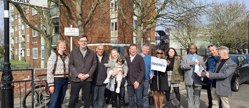 Group of residents in Ealing outside block of flats, with a "Citizens UK" flag