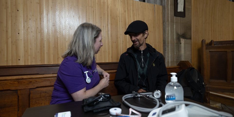 Parish nurse talking to a patient. Medical equipment laid out in front of them